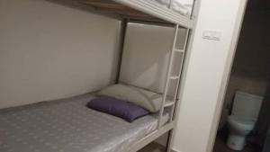 a bunk bed in a small room with a toilet at Tasneem Guesthouse in Shah Alam