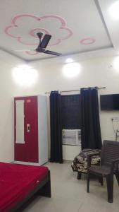 a room with a bed and a chair and a ceiling at Laxminarayan Sadan in Ayodhya