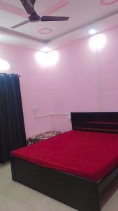 a bedroom with a red bed with a ceiling fan at Laxminarayan Sadan in Ayodhya