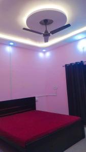a room with a ceiling fan and a red bed at Laxminarayan Sadan in Ayodhya