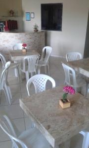 a restaurant with white tables and white chairs at Pousada Central in São Benedito