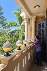 a man standing next to a row of spheres on a house at Perfume Homestay Huế in Hue