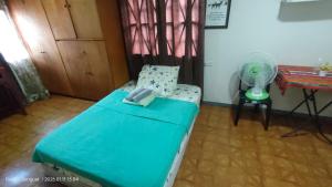 a room with a bed and a fan and a table at Kochimoto Homestay in Baguio