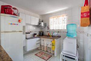 a small kitchen with white cabinets and a refrigerator at Casa de Vila Duplex, perto do Centro in Araruama