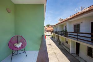 a pink chair sitting on the balcony of a building at Casa de Vila Duplex, perto do Centro in Araruama