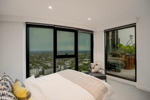 a bedroom with a bed and large glass windows at Sky One Grand Terrace Penthouse in Box Hill