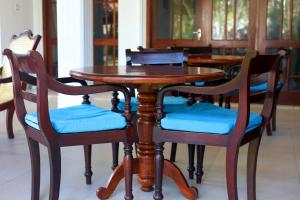 a wooden table and chairs with blue cushions at Surf Villa Hikkaduwa in Hikkaduwa