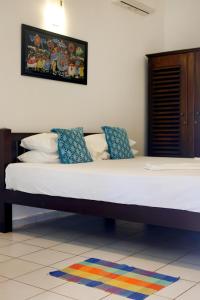 a bedroom with a large bed with white sheets and blue pillows at Surf Villa Hikkaduwa in Hikkaduwa +45 photos
