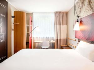 a hotel room with a white bed and a desk at Ibis Gdansk Stare Miasto in Gdańsk