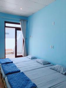two beds in a room with a blue wall at Bot Bien Homestay in Mui Ne +32 photos