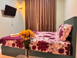 a bedroom with a bed and a vase of flowers on a table at Cio Adventure Hotel in Berastagi +6 photos