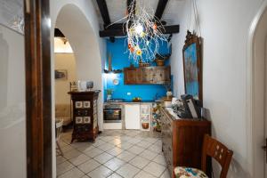 a kitchen with blue walls and a ceiling with a chandelier at Syrakosia a Ortigia in Syracuse