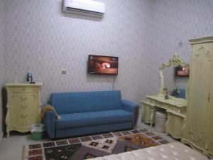 a living room with a blue couch and a tv at العين الهيلي مصباح بيت 13 in Al Ain