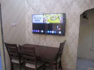 a television on a wall with a table and chairs at العين الهيلي مصباح بيت 13 in Al Ain +10 photos