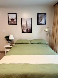 a bedroom with a green bed with pictures on the wall at The Vibe BGC Uptown Apartment in Manila +7 photos