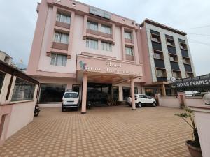 a large pink building with cars parked in front of it at Kanta International near katra railway station in Katra