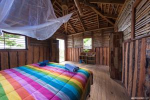 a bedroom with a rainbow bed in a wooden room at Fanifo Lofa in Ha’apai