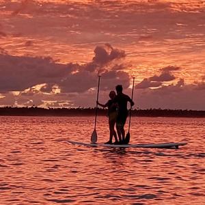 two people standing on a paddle board in the water at Fanifo Lofa in Ha’apai