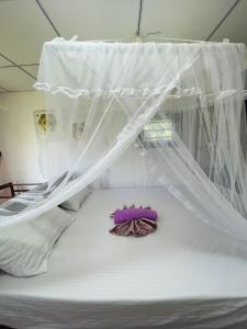a bed with a canopy and a purple pillow on it at Siri Niwasa Sky Villa in Ahangama