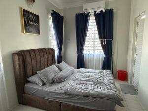 an unmade bed in a bedroom with blue curtains at Villa SRC in Sungai Petani