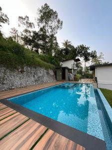 a swimming pool with a wooden deck next to a house at Camplights Stays in Tariyod