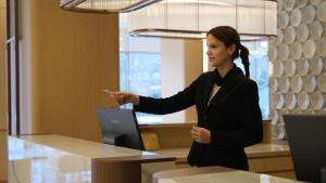 a woman standing in front of a counter holding a cell phone at Buyuk Saruhan Hotel in Manisa