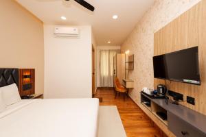 a hotel room with a bed and a flat screen tv at THE CONTINENTAL INN & SUITES in Mysore