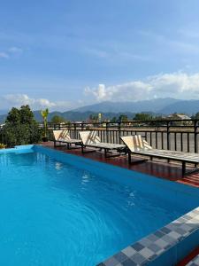 a swimming pool with two benches at Vang Vieng Sisavang Hotel in Vang Vieng