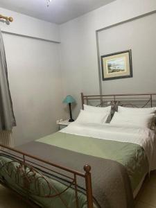 a bedroom with a bed with white sheets and a green blanket at Χαίρε, ξεΐνε, παρ' αμμι φιλησεαι in Tríkala