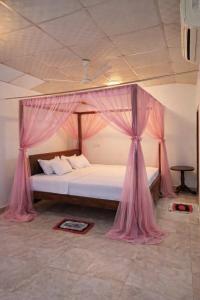 a bedroom with a canopy bed with pink curtains at Royal Villa in Ahangama