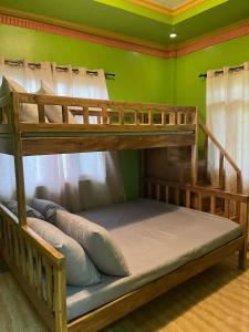two bunk beds in a room with a green wall at LobocAirbnb Travellers Inn in Loboc