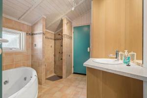 a bathroom with a tub and a sink and a shower at 1445 Aakirkeby - Poserekrogen 13 in Vester Sømarken +14 photos