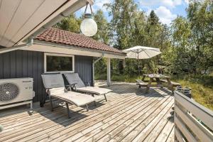 a wooden deck with a picnic table and an umbrella at 1445 Aakirkeby - Poserekrogen 13 in Vester Sømarken