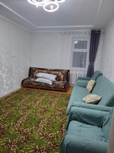 a living room with a couch and a green rug at Квартира in Karakol +1 photo