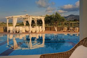 una piscina con mesa, sillas y un dosel blanco en Paradise Island Villas en Hersonissos