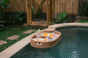 a tray of drinks in a basket next to a swimming pool at Sunrise Hill Bamboo House-Private Jungle Villa in Sidemen