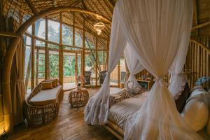 a bedroom with a canopy bed in a tree house at Sunrise Hill Bamboo House-Private Jungle Villa in Sidemen