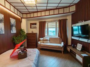a living room with a bed and a tv and a couch at Okaeri Place - One Regis in Bacolod