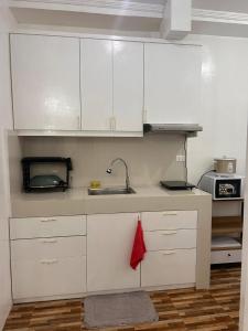 a kitchen with white cabinets and a sink at Kole & Kobe Haven in Dipolog