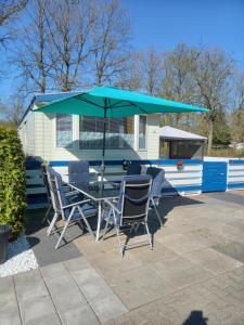a table and chairs under an umbrella on a trailer at stacaravan nr16 is 5 persoons in Schoonloo
