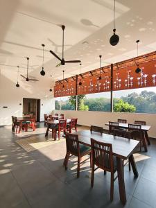 a restaurant with tables and chairs and large windows at Vaigayi Ayurveda and Yoga Resort in Kodanad