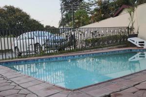 a swimming pool with a fence and a car at The Luxe Studio in Lusaka