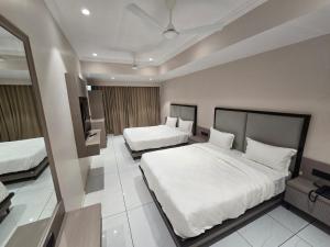 a hotel room with two beds and a mirror at Hotel Shivalik inn in Ankleshwar