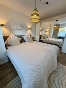 a bedroom with a large white bed and a mirror at Ferienwohnung Nordig in Garding