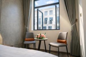 a room with a bed and two chairs and a table with flowers at Vinh Home Apartment in Quang Tri