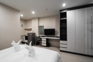 a bedroom with a white bed and a desk at Prajan Residence in Buriram