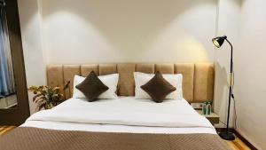 a bedroom with a bed with white sheets and pillows at Hotel Vilaasitaa inn Ujjain in Ujjain