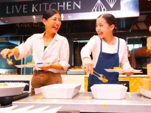 two women standing in a kitchen preparing food at Hotel Flags Sasebo KujuKusima in Sasebo