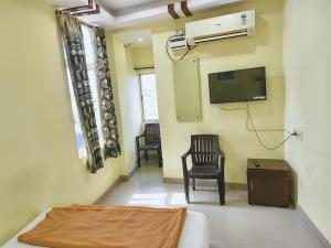 a room with a bed and a tv and two chairs at KEBA Dream Grand in Secunderabad