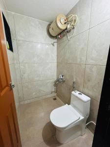 a small bathroom with a toilet and a light on the wall at Mangalore serviced flats in Mangalore +11 photos